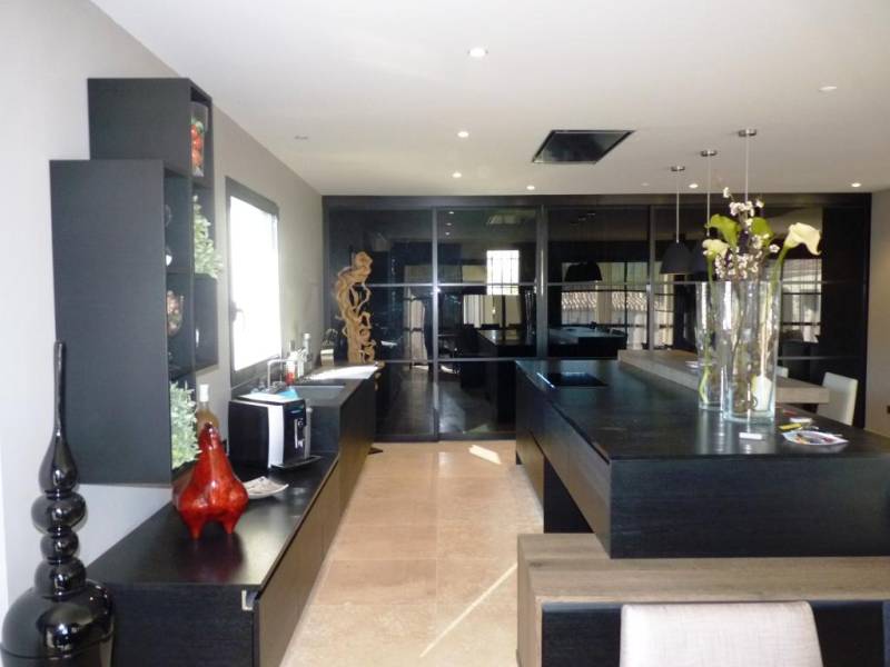 cuisine avec plan de travail en granit haut de gamme façades chêne teinté noir et portes coulissantes en verresur Nîmes dans le Gard