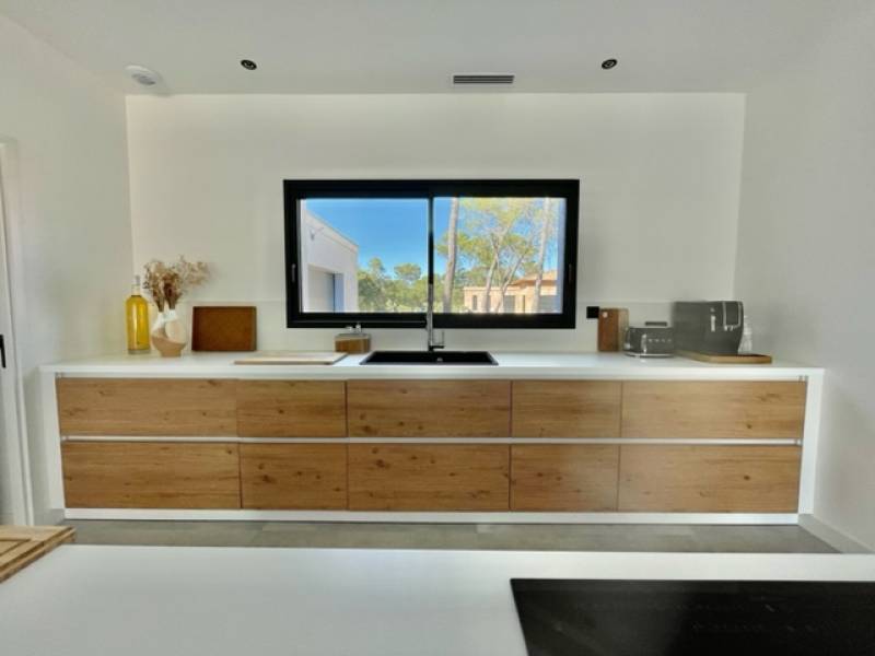 cuisine blanche et bois naturel avec un îlot central moderne installé chez notre cliente vue sur le linéaire mural à Nîmes près de Montpellier